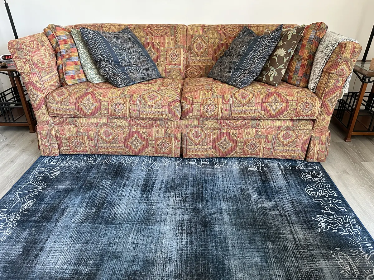 A patterned couch with blue cushions on an indigo rug