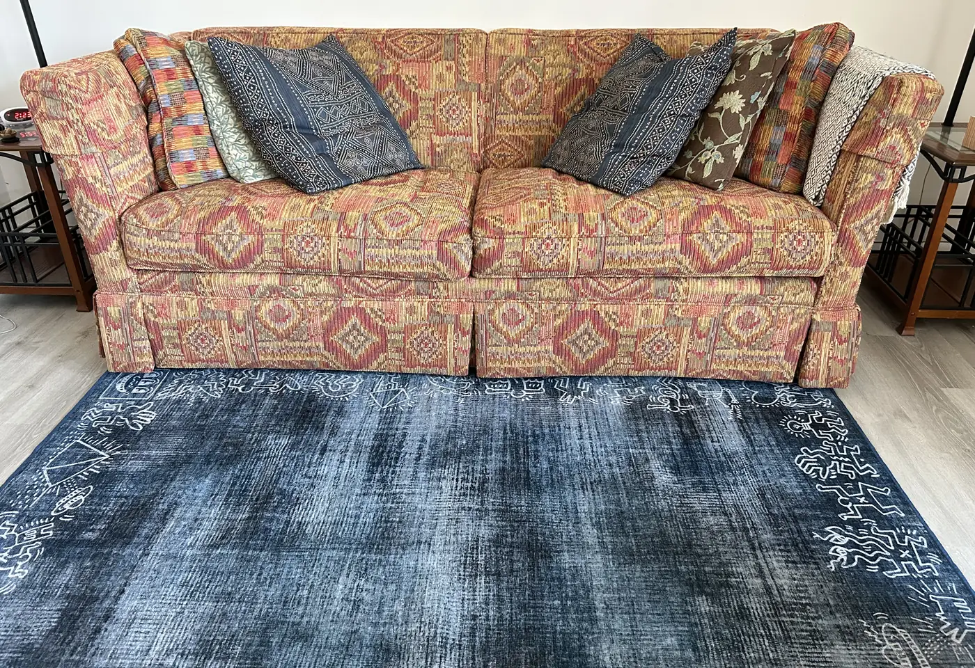 A long patterned couch with blue cushions on an indigo rug in Kara's office